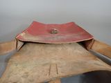 an old leather saddle with a red leather strap and a metal buckle