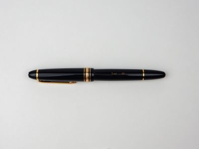 un stylo noir aux finitions dorées posé sur une surface blanche