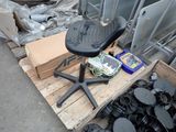 une chaise noire posée sur une palette, à côté d'un tas d'ordures
