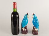 two figurines of birds sitting next to a bottle of wine