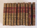 six vieux livres sont alignés sur une surface blanche