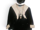un manteau et un chapeau noirs et blancs suspendus à un cintre sur un mur blanc