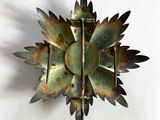 une broche en forme de fleur en métal sur un fond blanc
