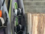 Plusieurs kayaks sont alignés contre un mur de briques dans un garage