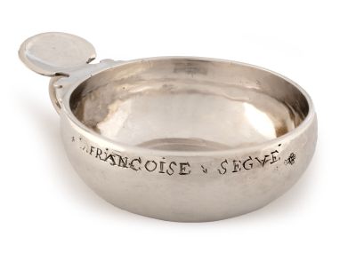 un bol en argent contenant une cuillère sur une surface blanche