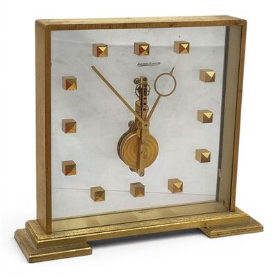 a gold clock that is on display on a table