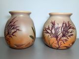 two vases sitting on a table with seaweed painted on them