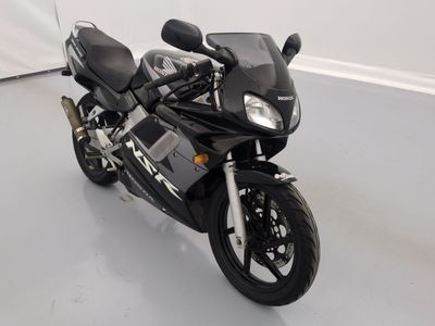 a black motorcycle parked in a room with a white wall