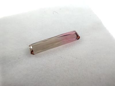 une photo d'une pierre en cristal rose et blanche posée sur un tissu blanc