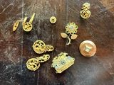 some gold jewelry on a wooden table with a button