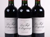 trois bouteilles de vin rouge posées l'une à côté de l'autre sur une surface blanche
