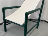 une chaise verte sur laquelle est posé un coussin blanc
