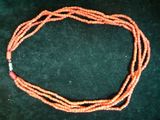 une image représentant un collier composé de perles orange sur un fond noir