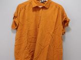 an orange shirt hanging on a hanger on a wall