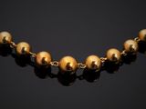 a gold beaded necklace on a black background