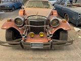a rusted car parked in a parking lot next to other cars