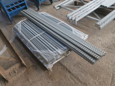 Plusieurs pièces d'acier sont empilées sur des palettes dans un entrepôt
