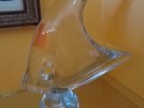 une sculpture en verre représentant un poisson, posée sur une table en verre