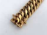 a close up of a gold bracelet on a white surface