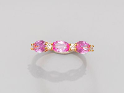 une bague en or sertie de pierres roses sur fond blanc
