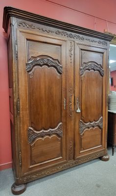 une grande armoire en bois dans une pièce où se trouve un miroir