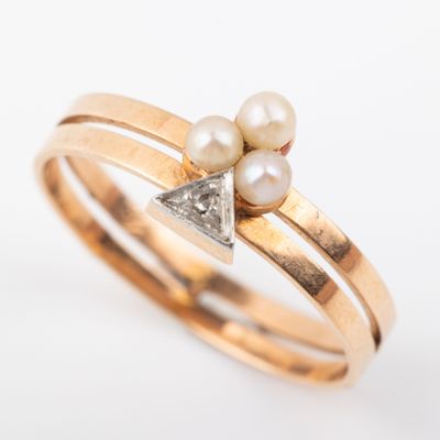 a close up of a gold ring with two pearls and a diamond