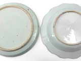 pair of blue and white plates with gold rims on a white surface