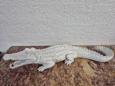 une statue représentant un alligator blanc assis sur une table