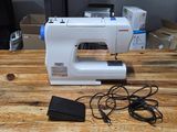 a sewing machine sitting on a wooden table next to a charger