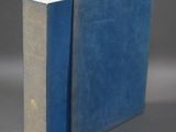 an old blue book sitting on top of a table next to a gray wall