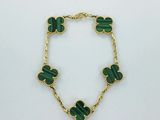 un bracelet vert orné de quatre breloques en forme de trèfle, montées sur une chaîne dorée