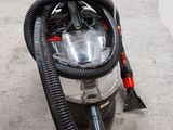 un gros plan d'un aspirateur muni d'un tuyau posé sur le sol