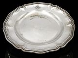 an antique silver plate on a black surface with a black background