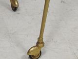 a gold metal table with a glass top on wheels