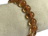 bracelet en perles de verre marron posé sur une serviette posée sur une nappe blanche