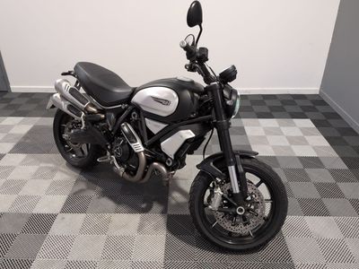 une moto noire et blanche garée sur un sol à damier