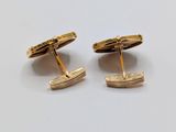 a pair of gold cufflinks on a white surface