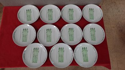 six white plates with green designs on them sitting on a red table