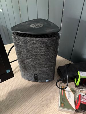 a black speaker sitting on a desk next to a monitor