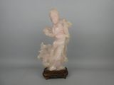 statue d'une femme tenant une fleur, posée sur un socle en bois