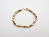 a gold bracelet with a braid design on a white background