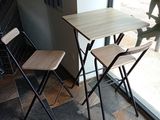 une petite table et deux chaises devant une fenêtre