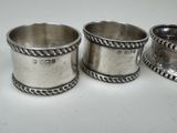 three silver cups with rope handles on a white surface