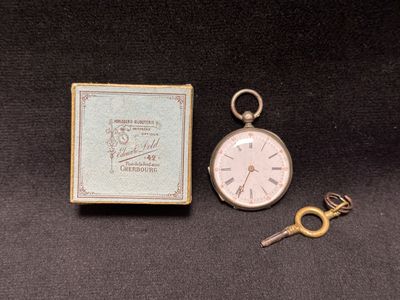 a pocket watch and a key sitting next to each other