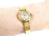 a woman ' s wrist that has a gold watch on it