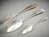 trois cuillères en argent et une fourchette sont posées sur une table