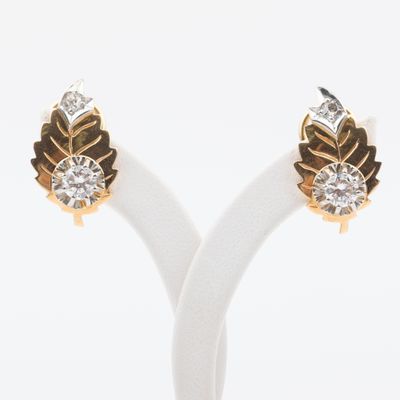 une paire de boucles d'oreilles en or et diamants posée sur un socle blanc