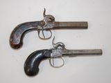 two old guns are sitting on a white surface next to each other