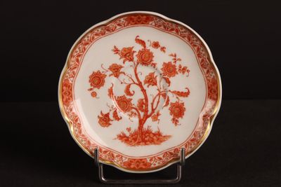an orange and white plate with flowers and birds on it