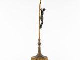 a bronze statue of a man on a pole with a spear